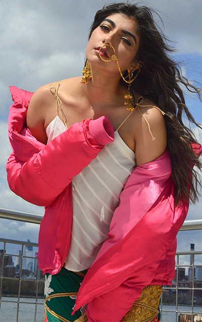 Short silk fuchsia puffer jacket and pleated top accessorized with South East Asian traditional style jewelry.