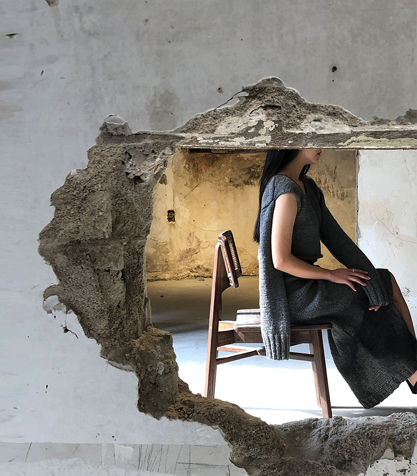 "Projection of living in the pain of war without losing hope. Collapsed cities, burnt buildings, lost lives, and respite in the sun. Harmony of exposure and cover from harm. Hand knit work, balance between distinctive construction and uncomplicated design of stitch. Hand dyeing enhances its uniqueness. "
