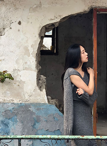 Cropped charcoal v-neck sweater, with a right front armhole opening detail, reflects cracks and gaps found on demolished buildings.