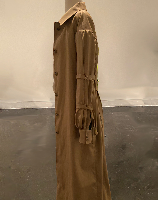 A side view of the long trenchcoat shows off the two D-ring strap details on the puff sleeve. The sleeve has a wide cuff and button closure.