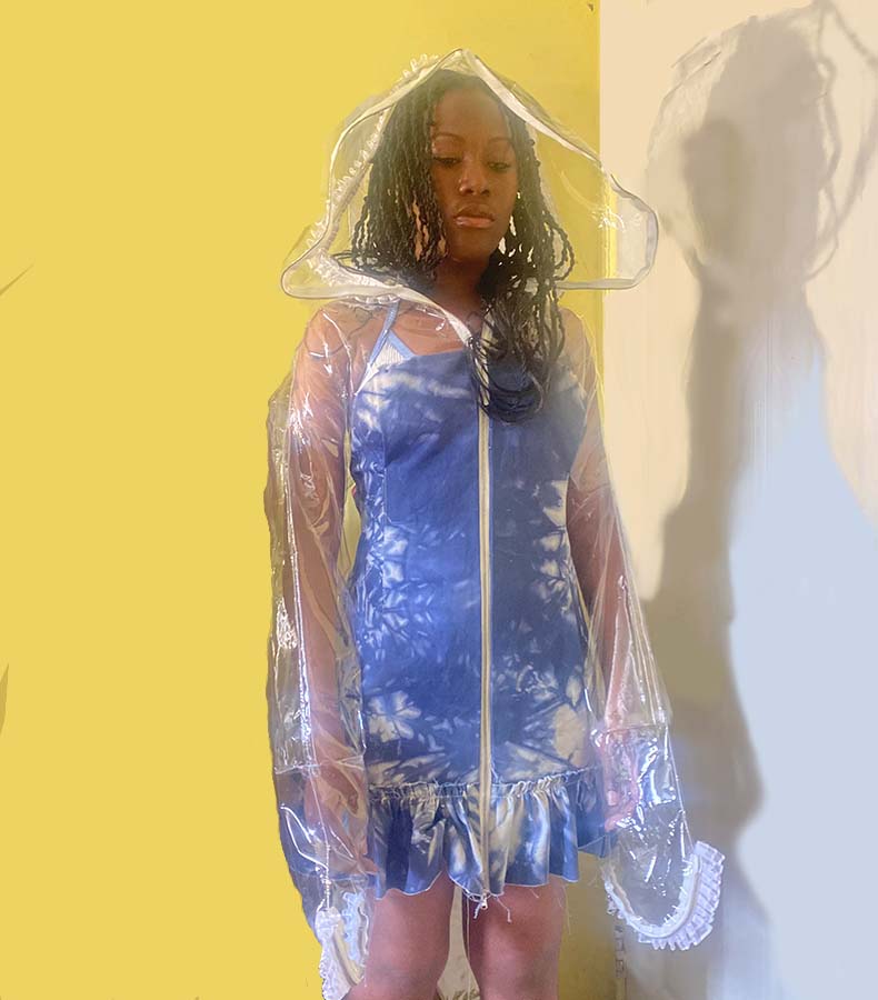 Front view of garment, a jacket dress. The top is a vinyl jacket hoodie with white lace trim detail. The dress also includes a zipper in the front.