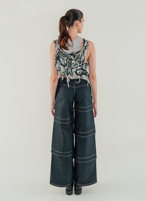 Full back view of model that shows the felted yarn tank in detail as well as the layered asymmetrical jeans 