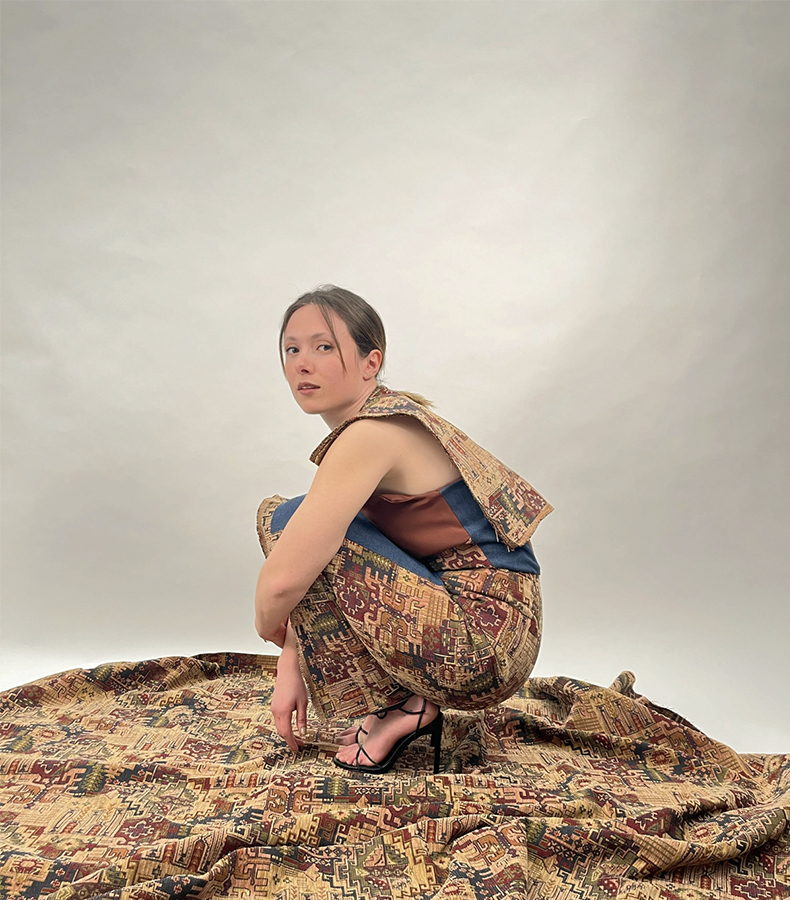 The model turned to the camera with her knees bent and her hands folded in front of her knees, just like in a fetal position, on the Turkish kilim-patterned fabric used in the design.