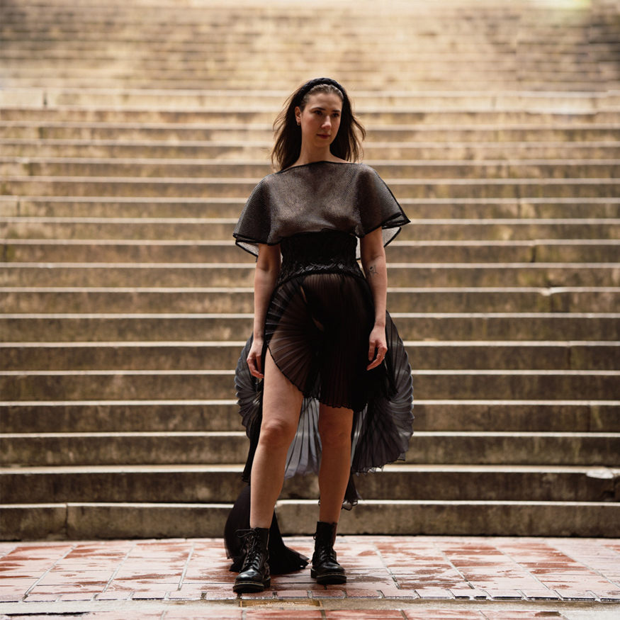 A front view of the dress where you can see the chainmail cape, which represents the heavy feeling of grief; the weaved corset, which represents the complicity of dealing with loss of a close one; and the pleated skirt, which I used in an unconventional way and created circler shapes to show the endlessness.