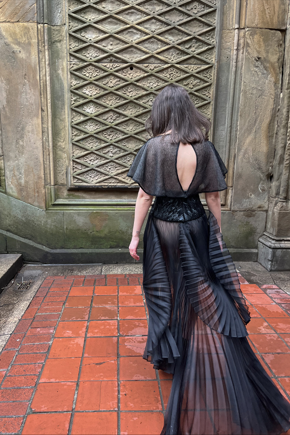 A back view where you can see the keyhole in the back of the cape and the movement of the pleated skirt