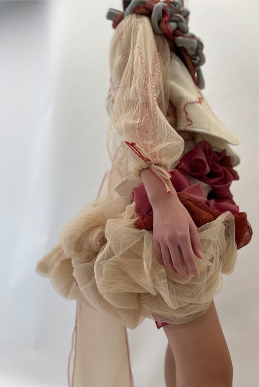 A short, suspended skirt loosely draped in a voluminous silhouette. The skirt slowly transitions from different hues of red into beige and white.