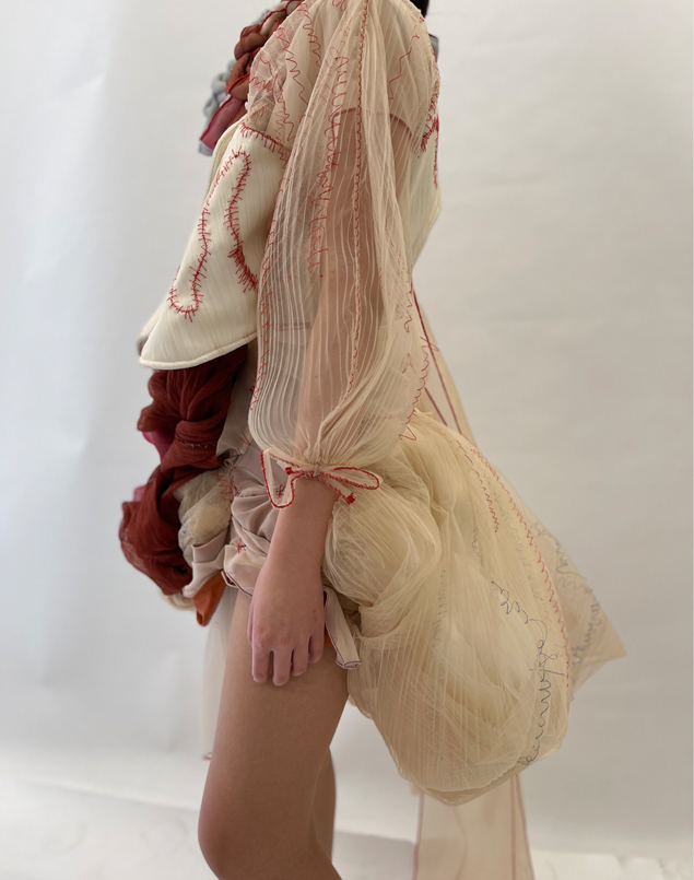 The pleated, gathered tulle sleeve extensively embroidered with red threads with adjustable ties.