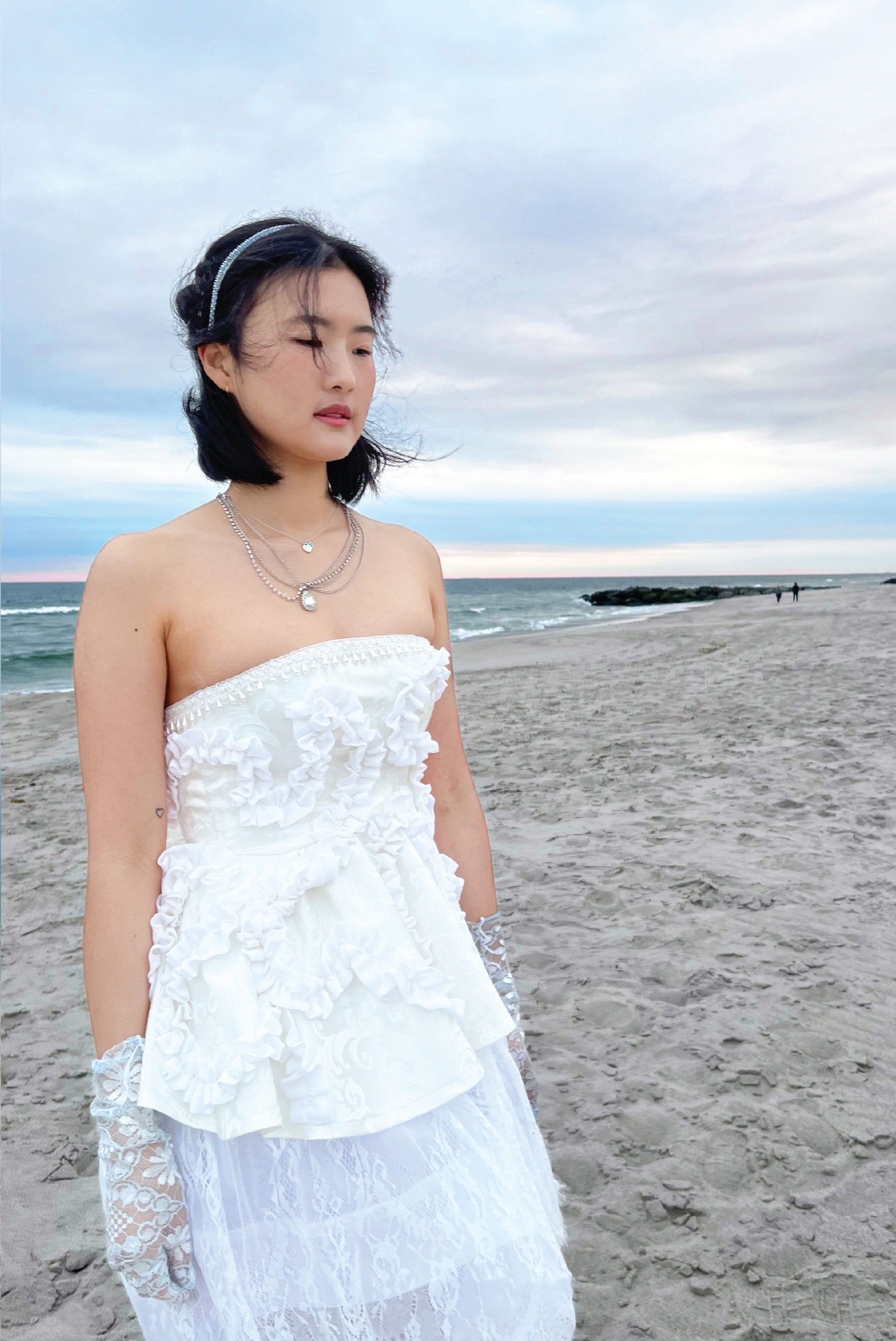 Model looks into the distance with the strapless dress and sky blue lace gloves. She is without the jacket in this photo.