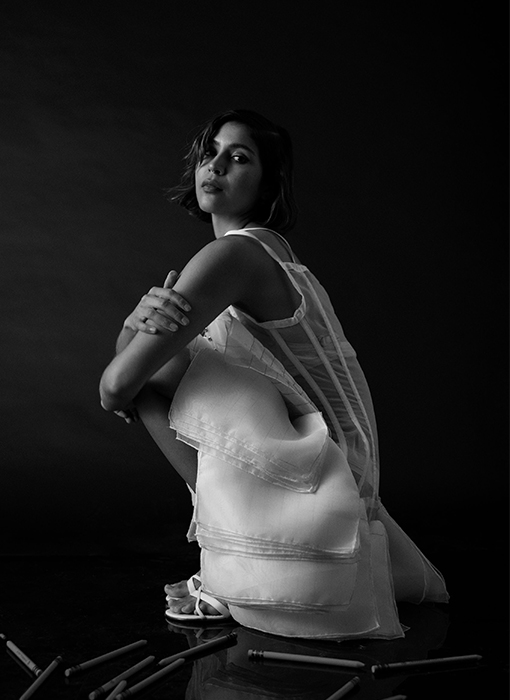 The model is posing in a side view, squatting position looking toward the camera, which makes the pages on the bottom of the dress fall in an overlapping manner.