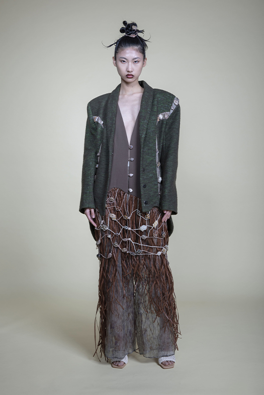 I used the hemp rope to weave the stone hem, and it's connected to the vest. I overlapped the rope and designed the shape like a mountain. The raffia represents plants and adds flowiness to the hem.