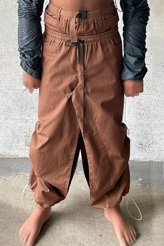 Convertible pants skirt. Nylon waistband. Encased elastic with knit cording and metal cord ends. Detailed close view of pants skirt.