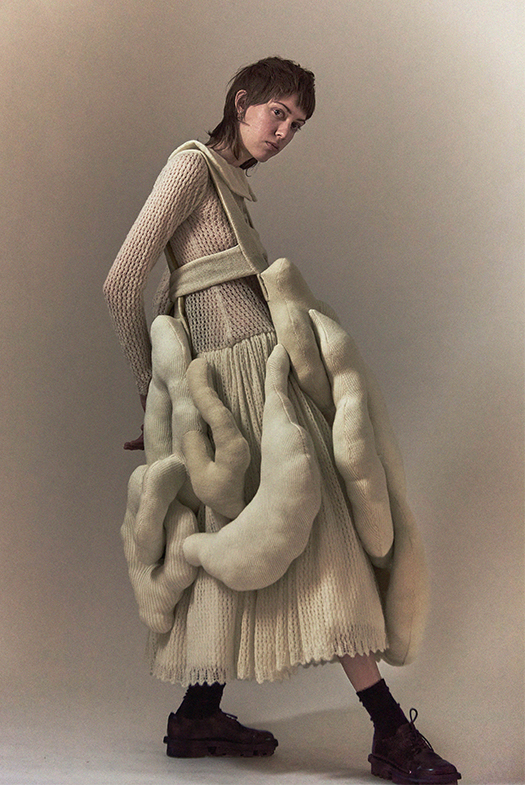 Side view of sculptural over piece and mohair dress