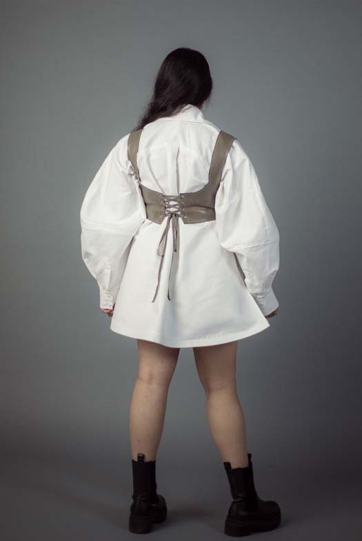  The back view of the previously described look demonstrates the lace-up back of the bralette, further showing the volume of the lantern sleeves, cuffed at the hem with a placket. 