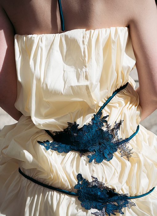 A close-up of the back of the gown. The lace has been invisibly hand-stitched to the dress. The back closes in a way that does not disturb the continuity of the poufs or reveal the understructure underneath.