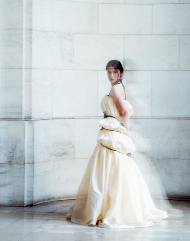 A side view of the woman. It's blurred, and her shadows appear besides her. The poufs travel along the body uninterrupted over the side seam. The woman is in the same alcove, and she's staring directly at the viewer.
