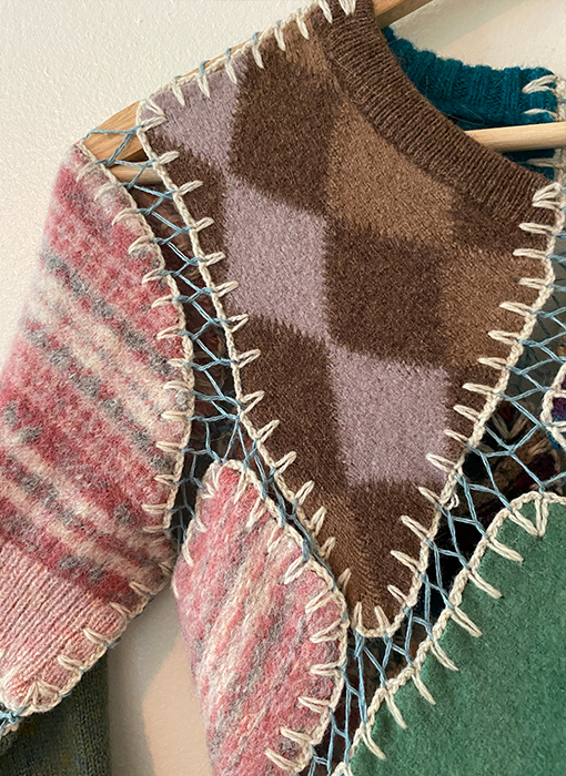 Close-up of the top left corner of the dress, showing a brown diamond pattern for the neckline and a pink Fair Isle sweater for the section below and the top of the sleeve